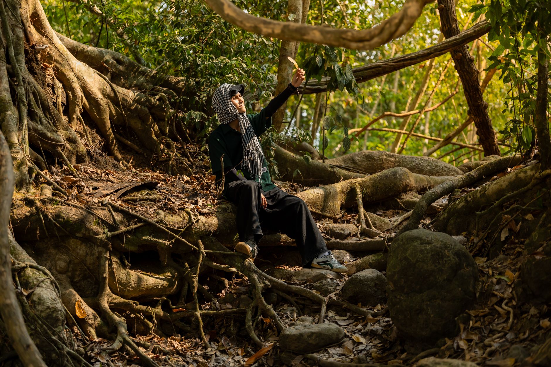 Individual sitting amid massive tree roots in Nam Cat Tien, Vietnam.