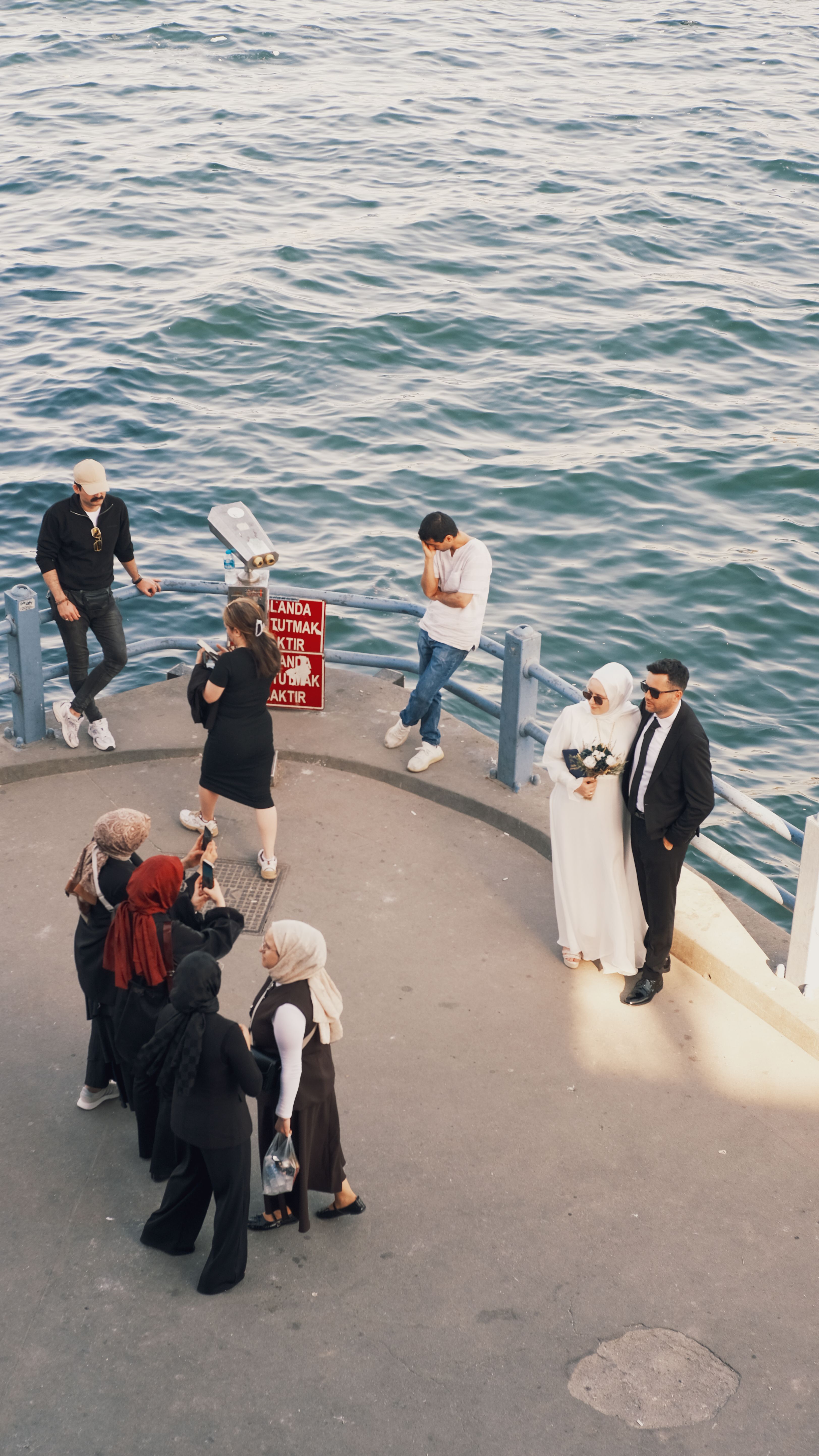 A group gathered at a seaside deck for a wedding photoshoot.