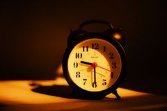 A classic black alarm clock under warm lighting, highlighting its vintage appeal and time display.