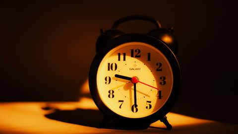 A classic black alarm clock under warm lighting, highlighting its vintage appeal and time display.