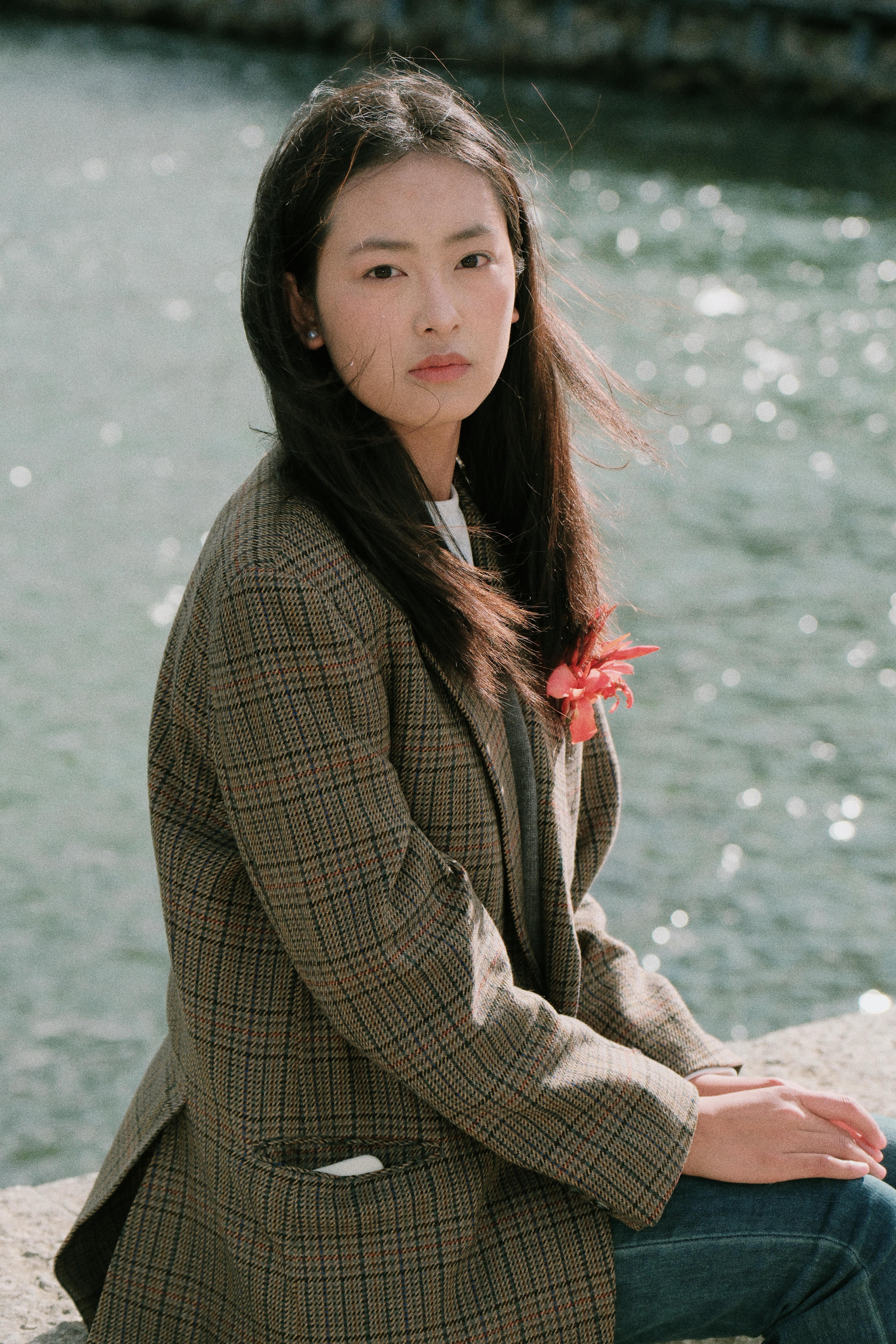 A serene portrait of a young woman sitting by a river, exuding calmness and grace.