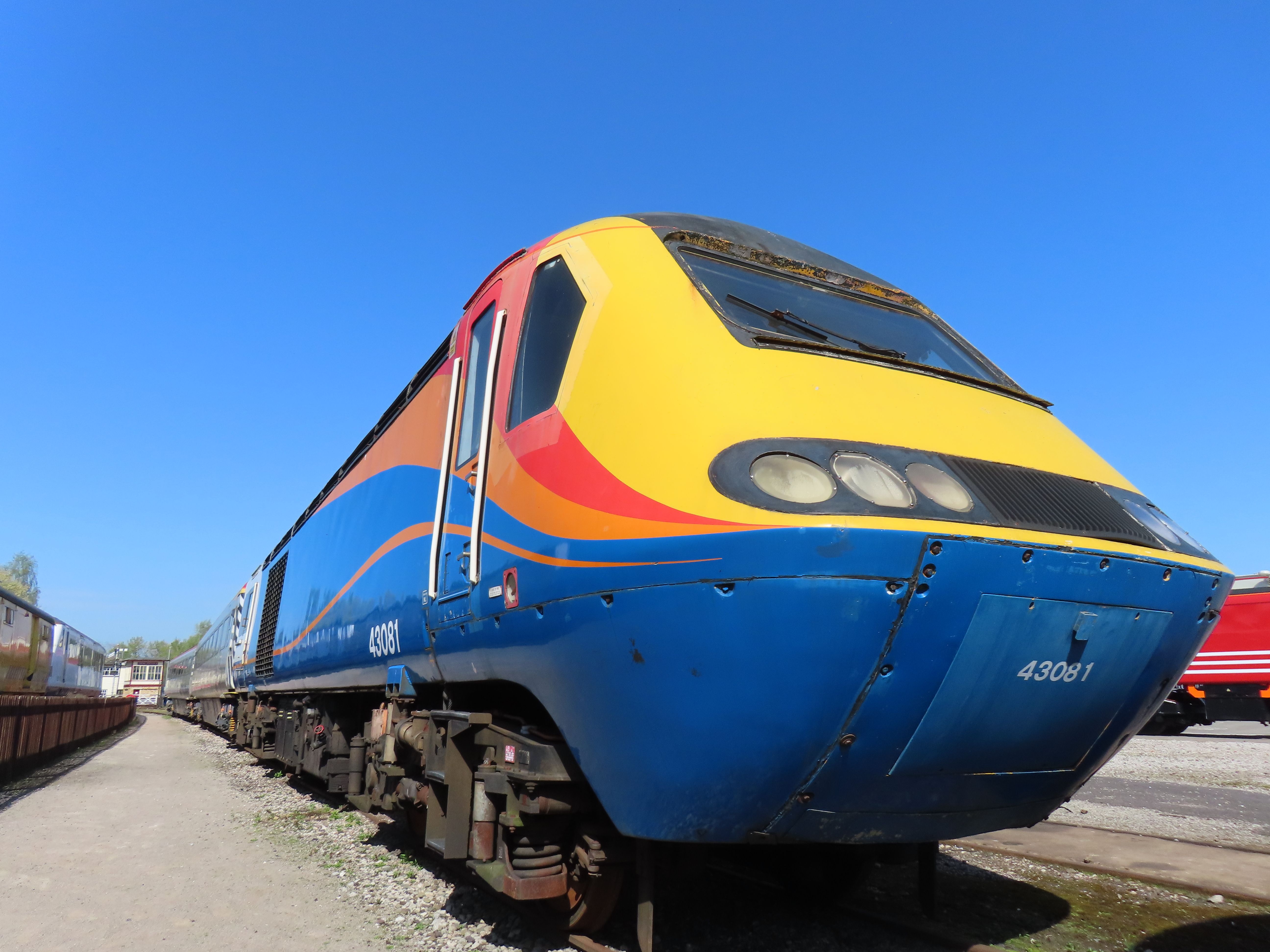 Vibrant train captured in England under a clear blue sky.