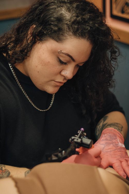 Free A focused tattoo artist crafting an intricate design on a client in a studio setting. Stock Photo