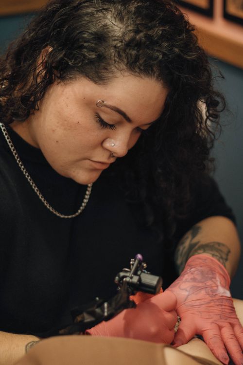 Free Close-up of a tattoo artist focused on her work, showcasing precision and artistry. Stock Photo