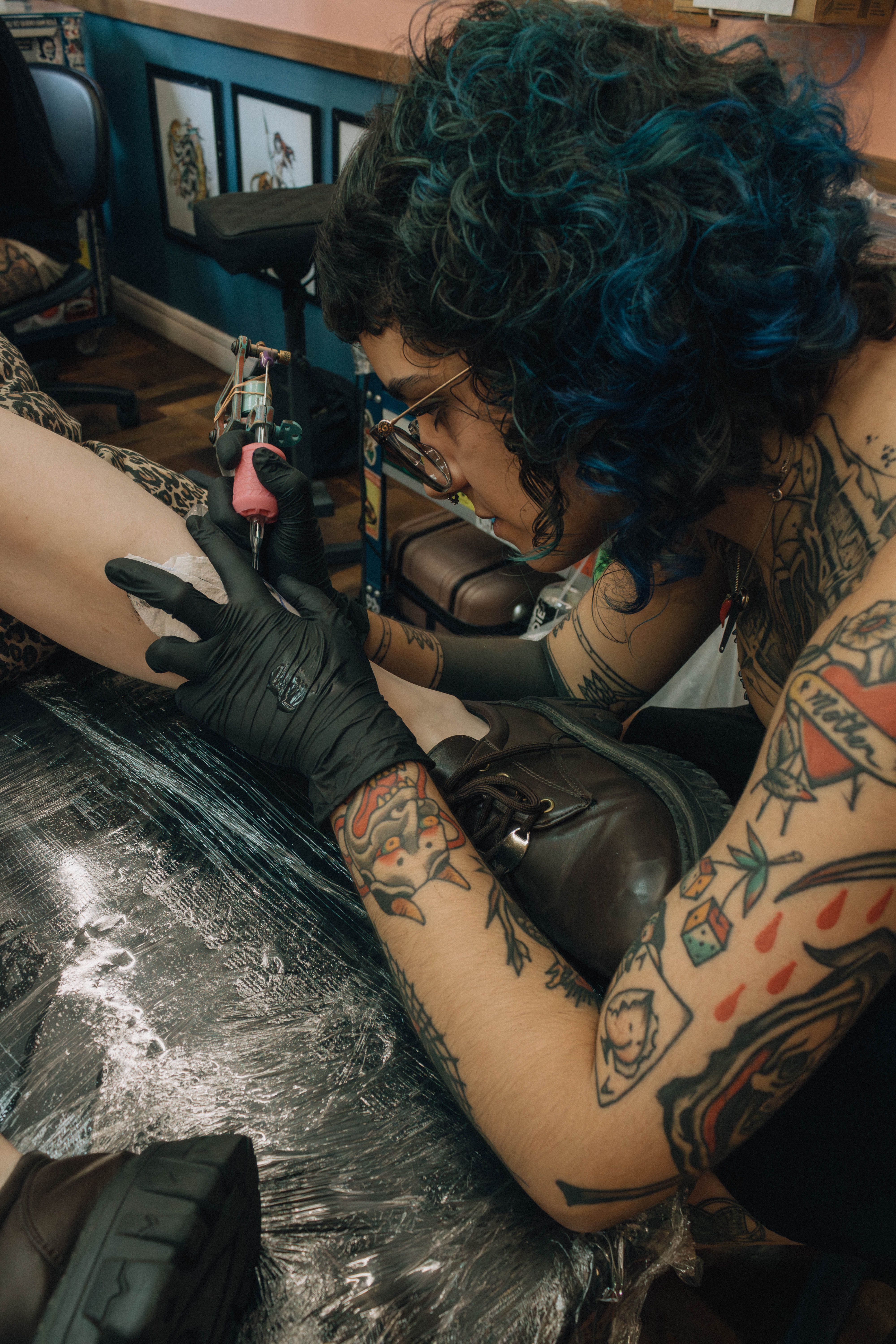 Tattoo artist skillfully creating a detailed design on a client's leg in a studio setting.