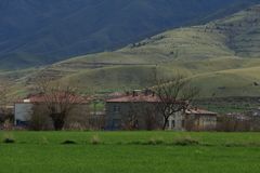 Idyllic rural scene with houses set against a backdrop of rolling green hills.