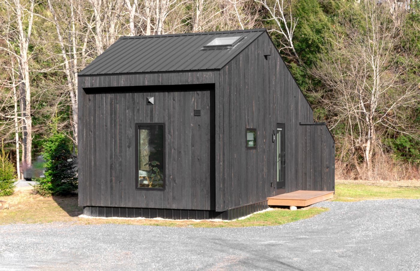 Modern black tiny house exterior in a wooded setting