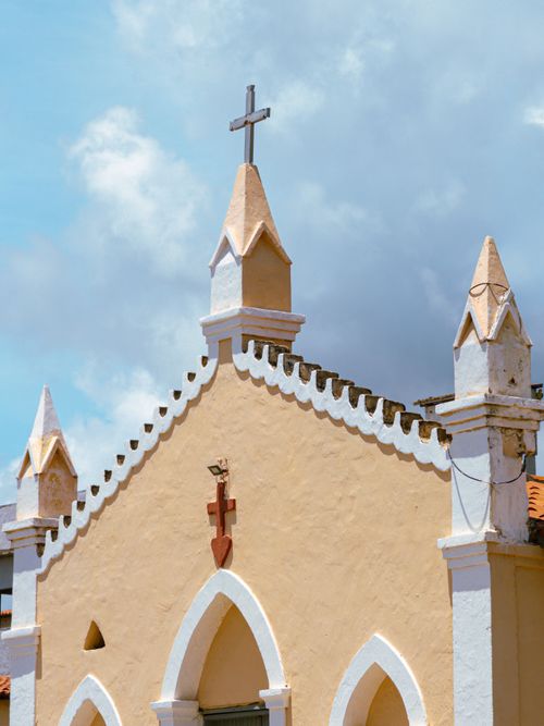 Free A quaint historic church with pointed towers and a cross stands against a vivid blue sky. Stock Photo