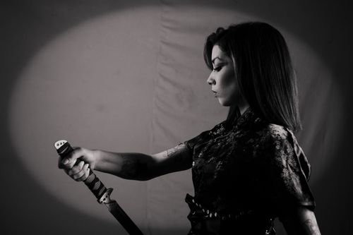 Free Artistic black-and-white portrait of a woman holding a katana, exuding strength and elegance. Stock Photo