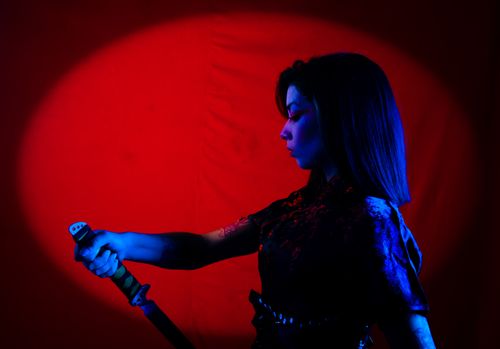 Free Moody artistic portrait of a woman holding a katana in dramatic lighting. Stock Photo