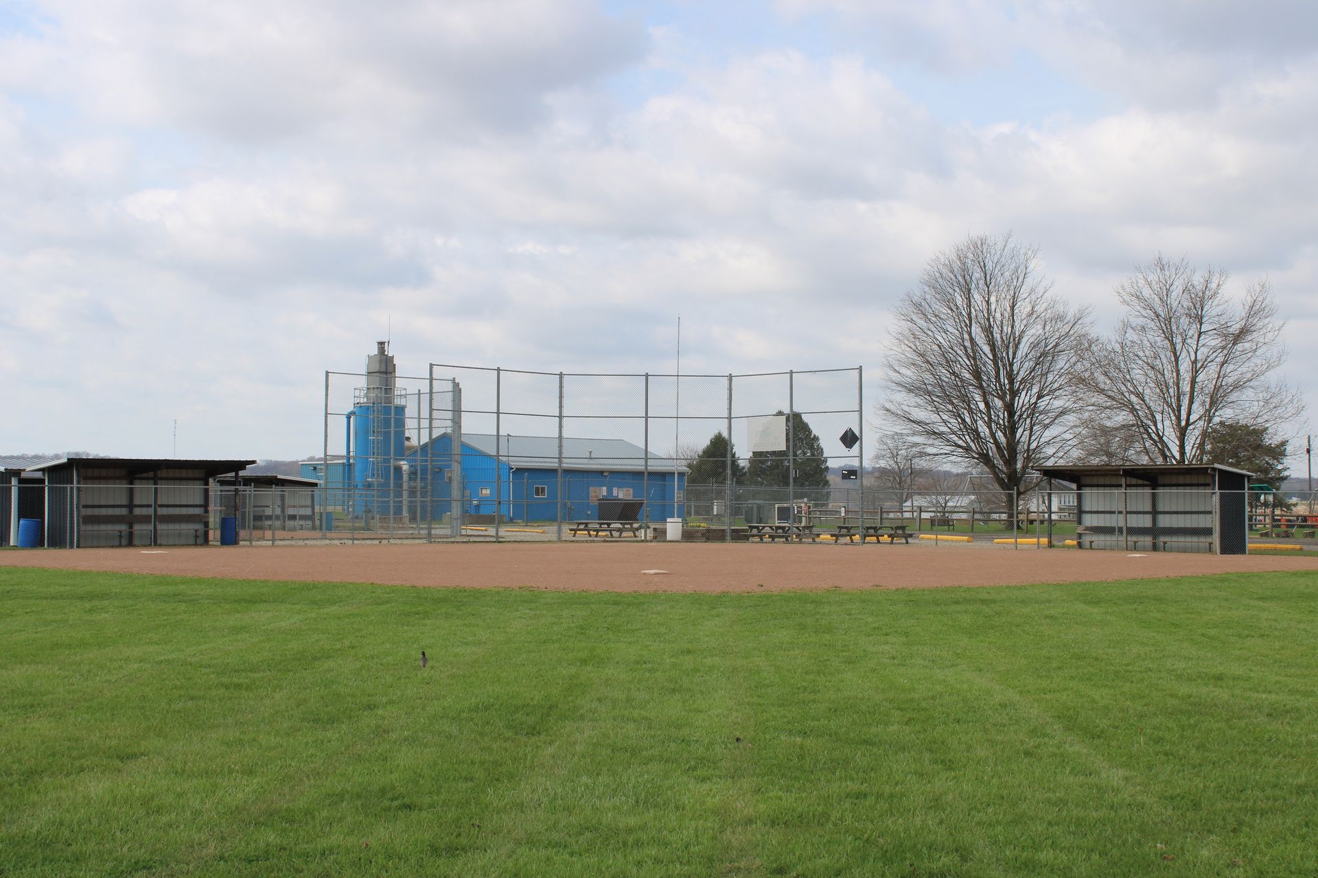 Campo de béisbol de pueblo pequeño con gradas vacías a plena luz del día