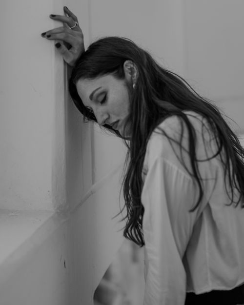 Free Black and white portrait of a thoughtful woman leaning against a wall. Stock Photo