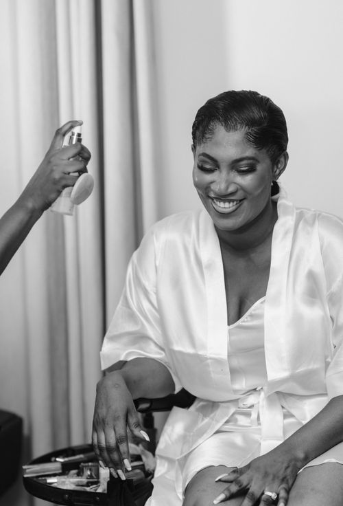 Free Smiling woman in satin robe having hair styled with spray, indoors. Stock Photo
