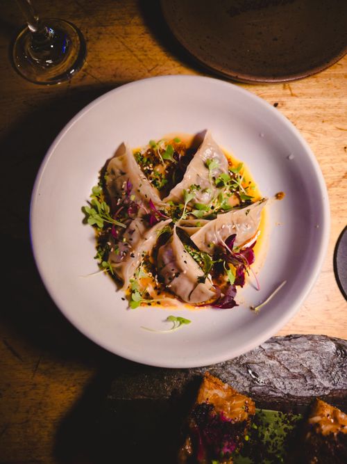 Free A plate of beautifully plated dumplings garnished with greens on a wooden table. Stock Photo