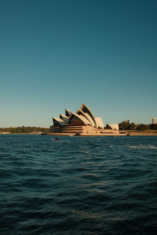 Free Stunning view of the iconic Sydney Opera House with clear blue skies and calm waters. Stock Photo