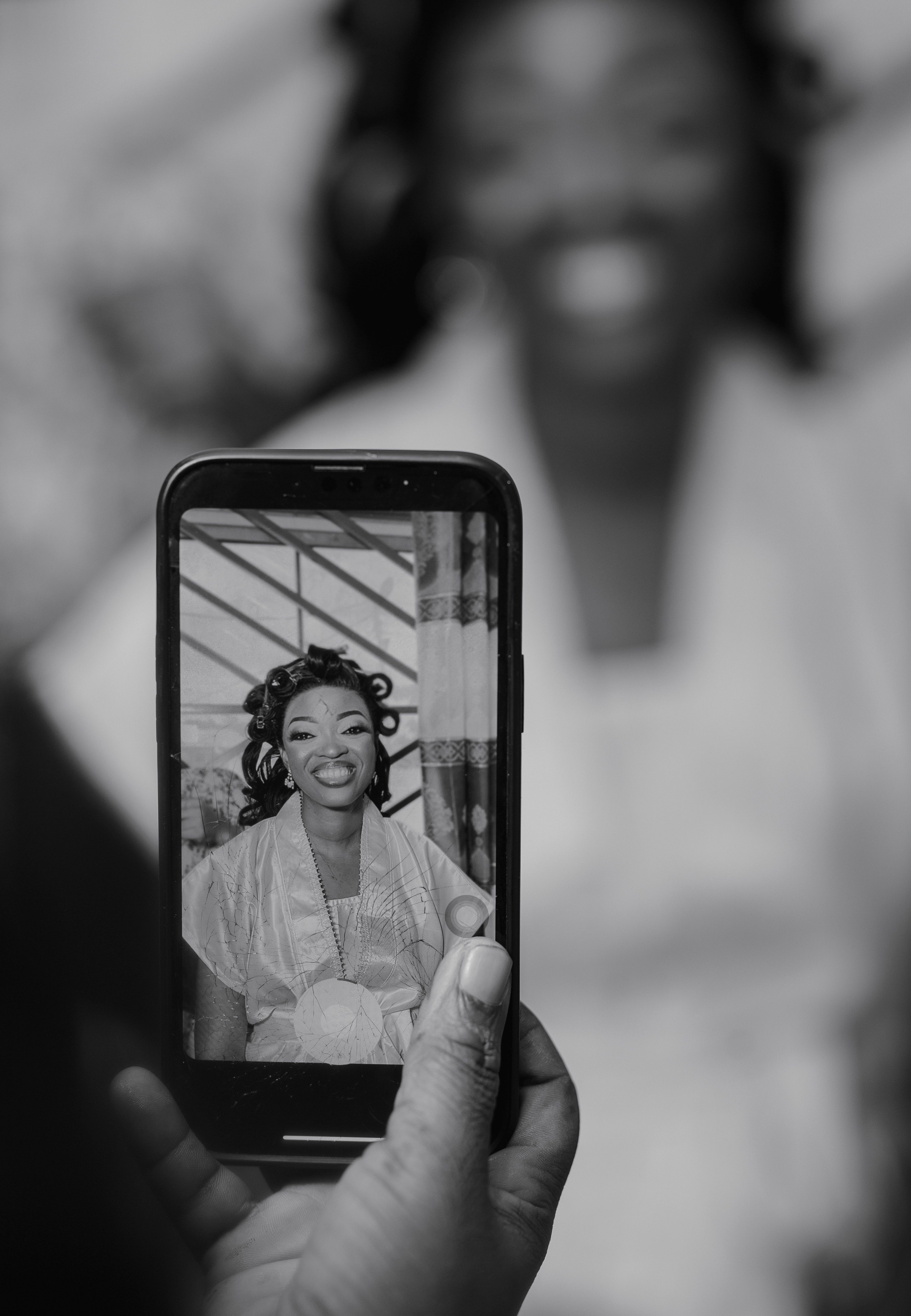 A woman smiling as her portrait is captured on a smartphone screen.