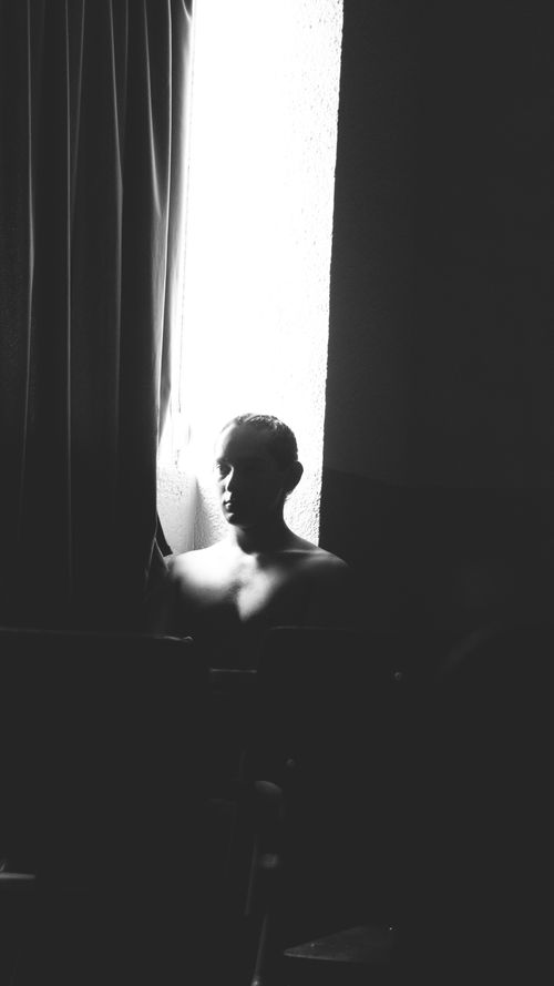 Free Moody black and white portrait of a person in silhouette by a window. Stock Photo