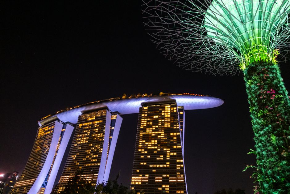 Stunning nighttime view of Marina Bay Sands hotel with illuminated Supertree in Singapore.