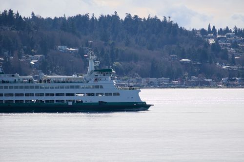 Free Ferry boat cruising in Puget Sound near Bainbridge Island, Washington, with forested hills in the background. Stock Photo