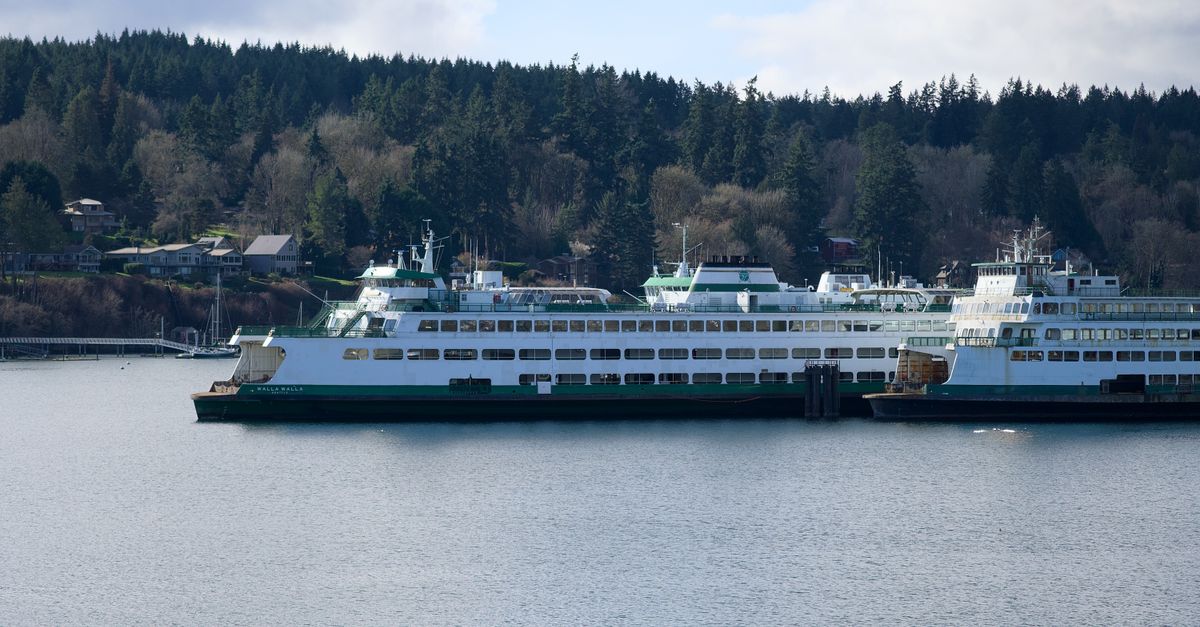 Scenic view of ferries docked at Bainbridge Island, surrounded by lush forests on a clear day.
