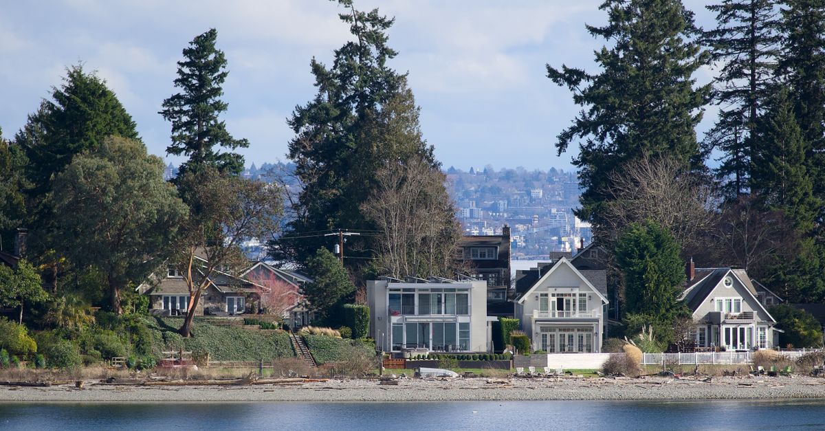 Charming waterfront homes along Bainbridge Island's beach, with lush trees and tranquil waters.