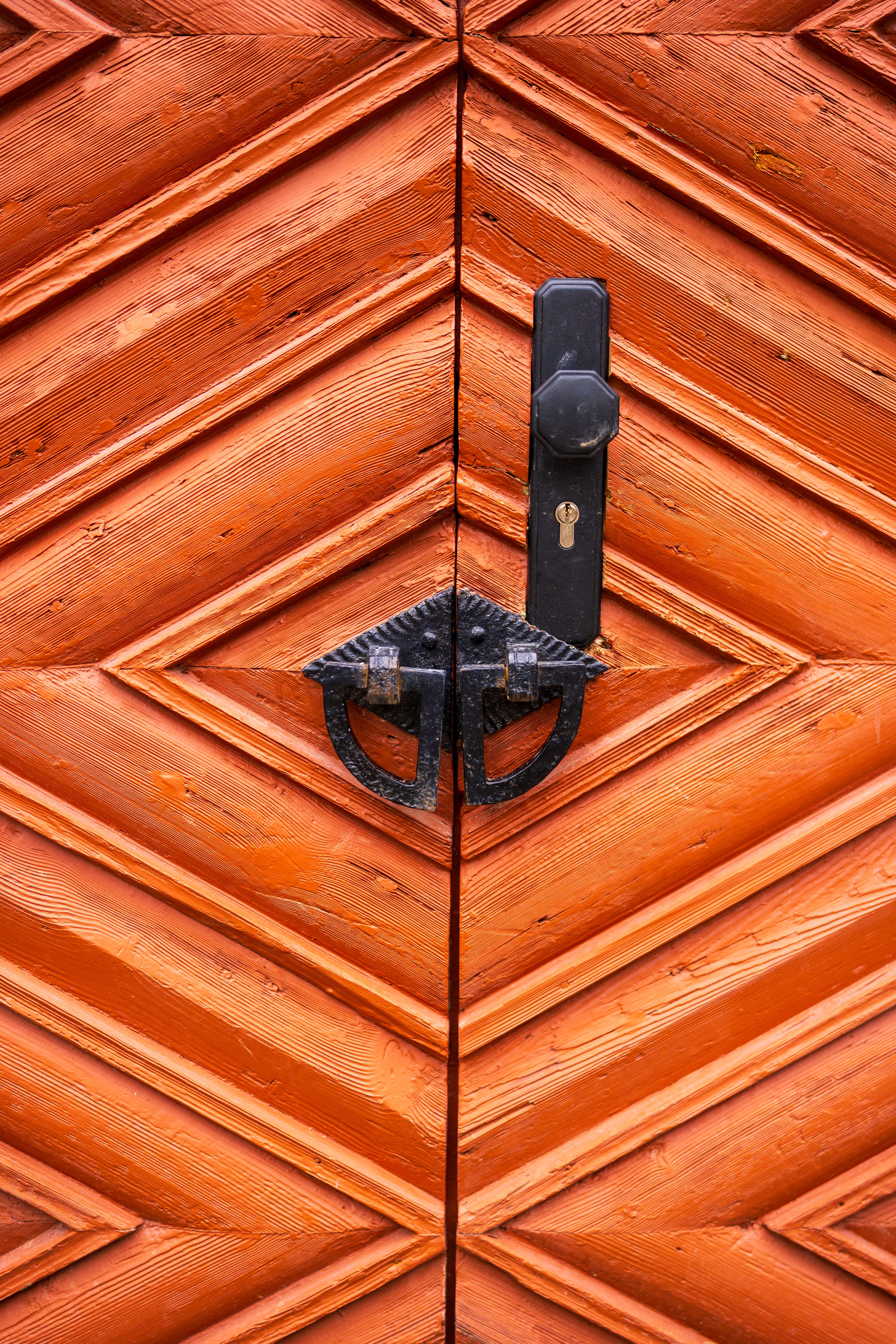 Detailed view of a chevron-patterned wooden door with a classic iron handle and lock.