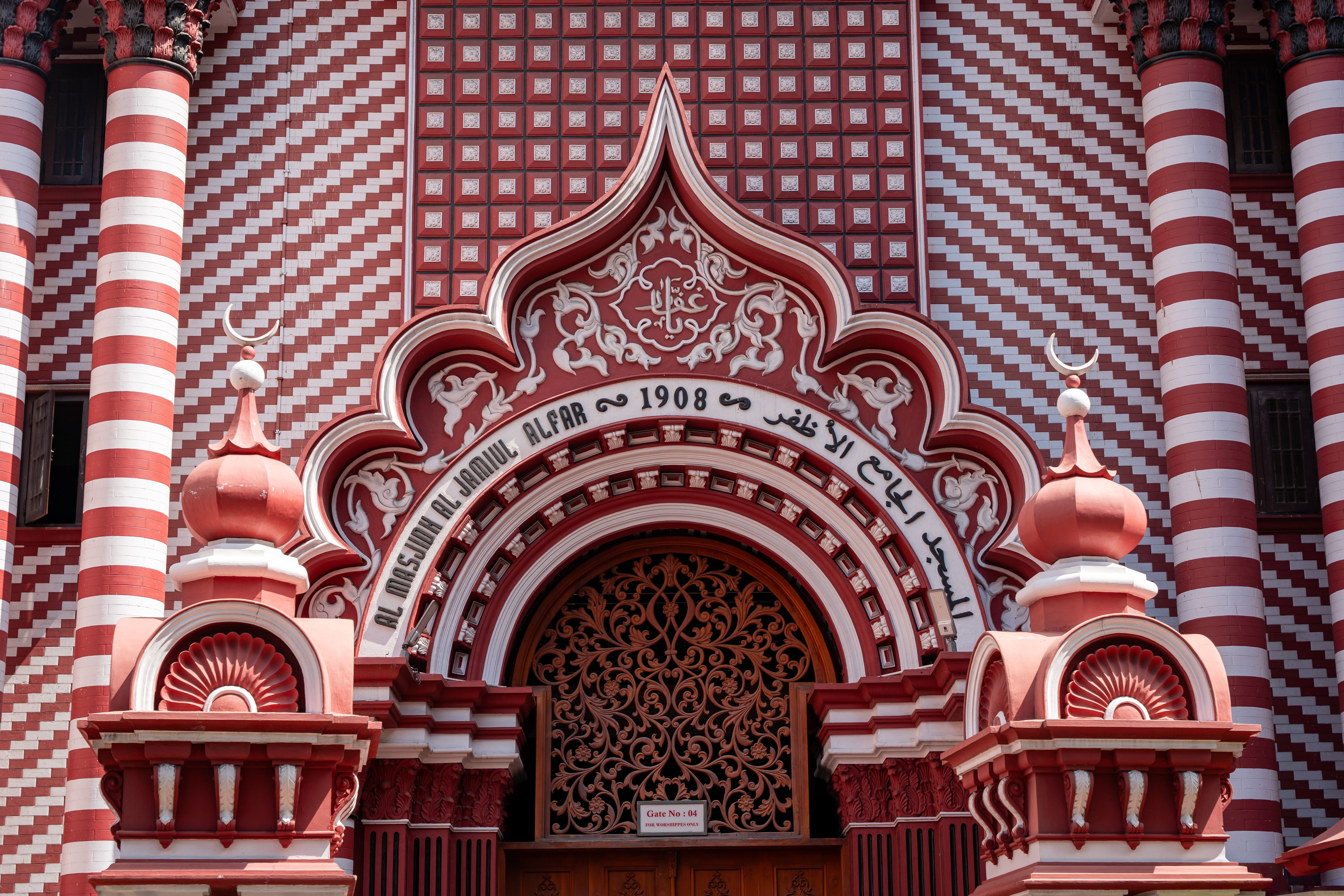 Intricate facade of Jami Ul-Alfar Mosque in Colombo with distinctive red and white stripes.