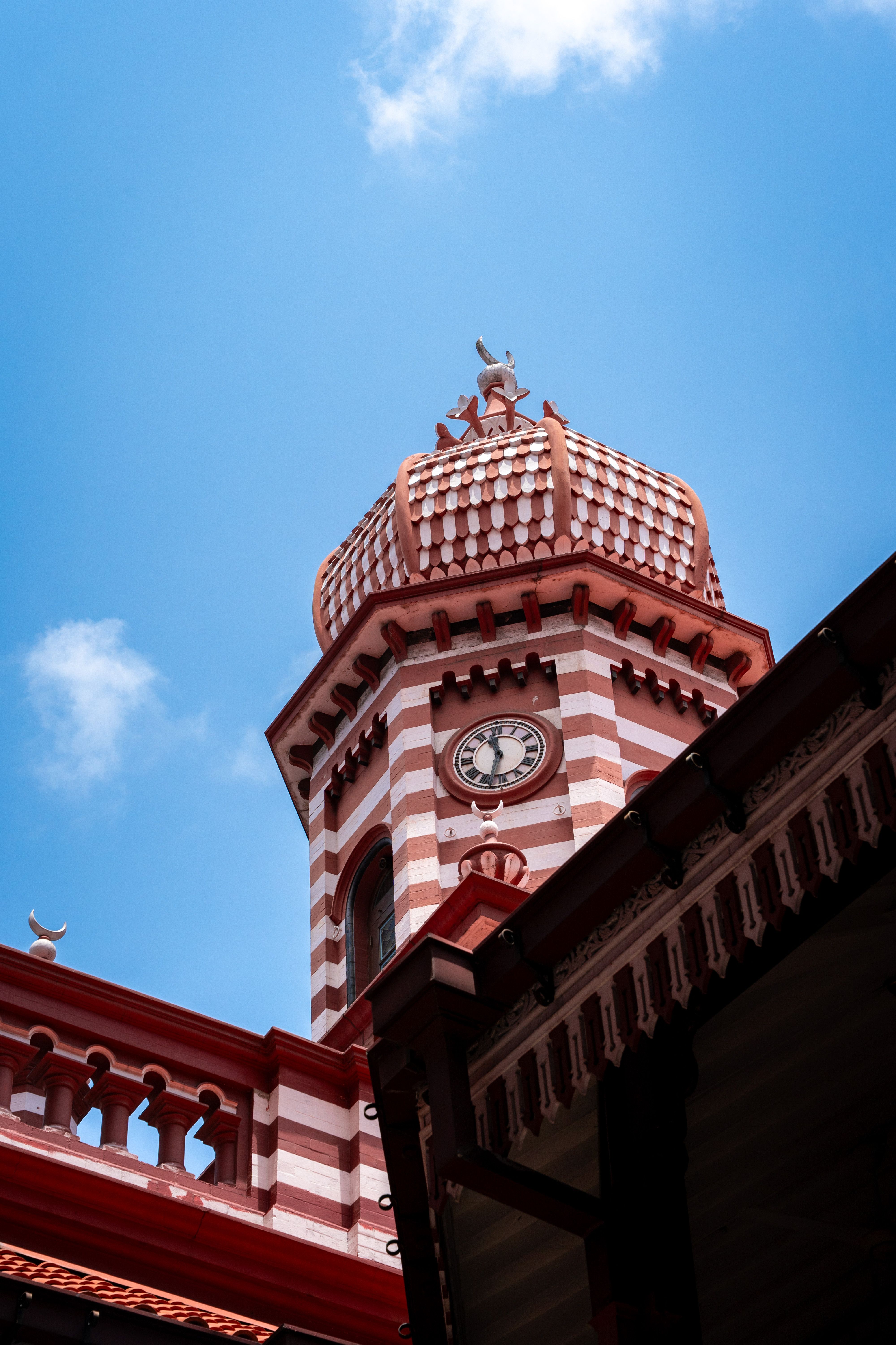 Striking view of the red and white striped dome of Jami Ul-Alfar Mosque in Colombo, under a bright blue sky.