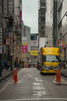 Street scene in Tokyo featuring a yellow delivery truck amidst urban architecture.
