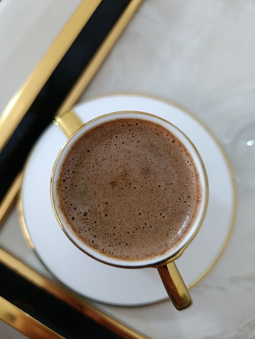 Free Aerial view of a coffee cup on a stylish gold-accented tray, creating a luxurious feel. Stock Photo