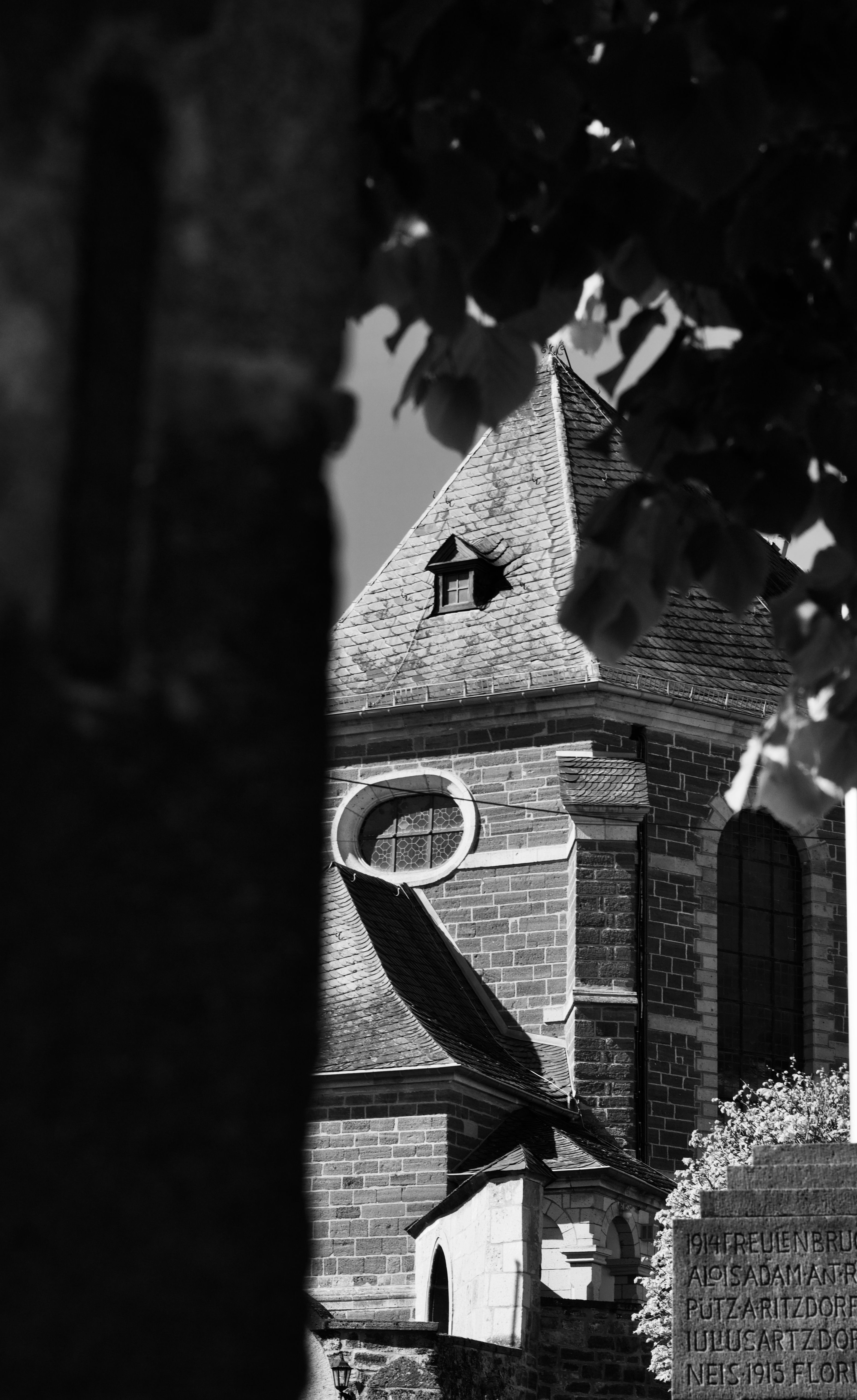 Black and white photo of an old church tower with stone architecture and gothic design.