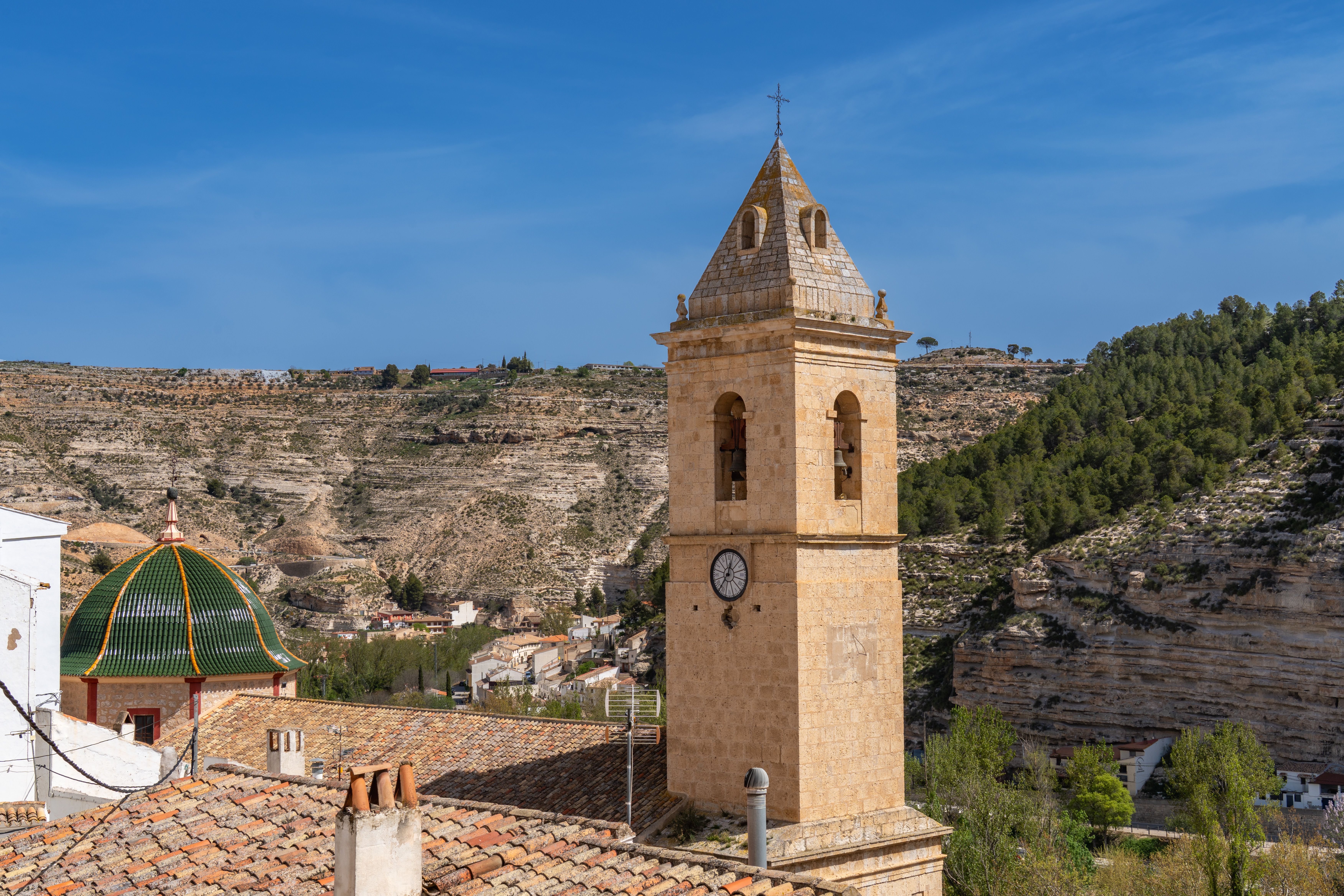 Charming bell tower with scenic landscape in Alcalá del Júcar, showcasing traditional Spanish architecture.