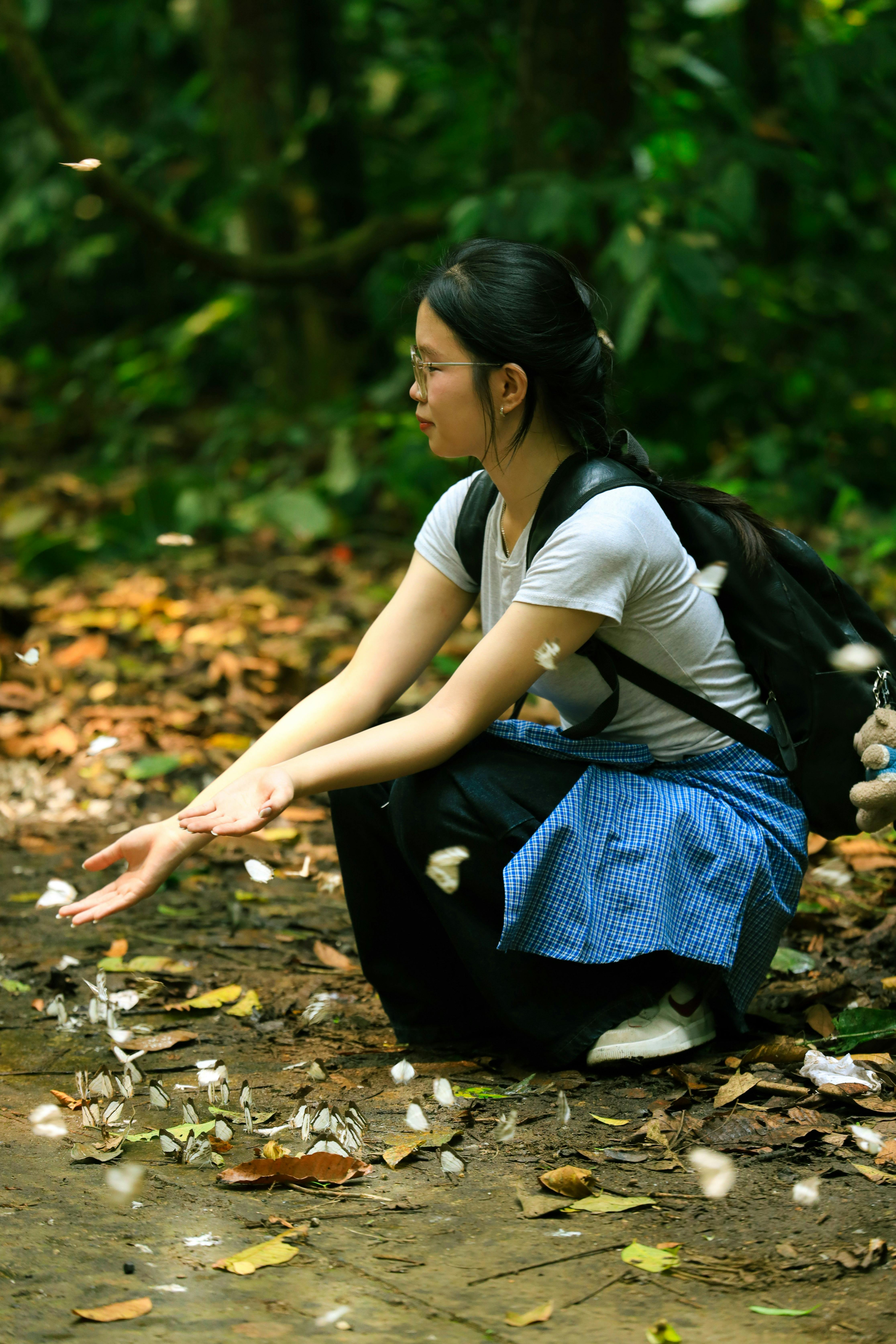 A woman interacts with butterflies on a forest path in Ninh Bình, Vietnam, showcasing nature's beauty.
