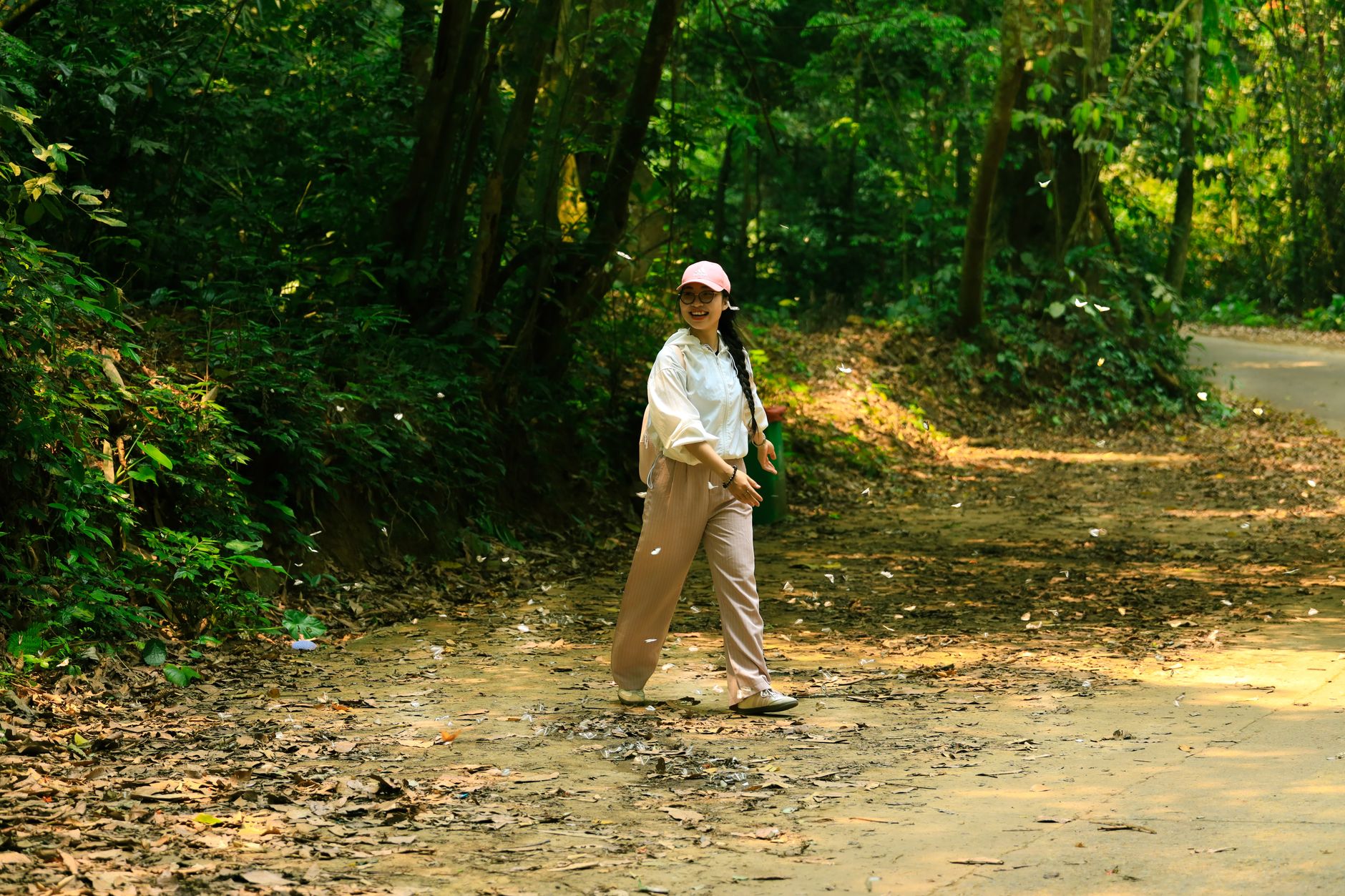 A woman smiling as she walks along a forest path in Ninh Bình, Việt Nam.
