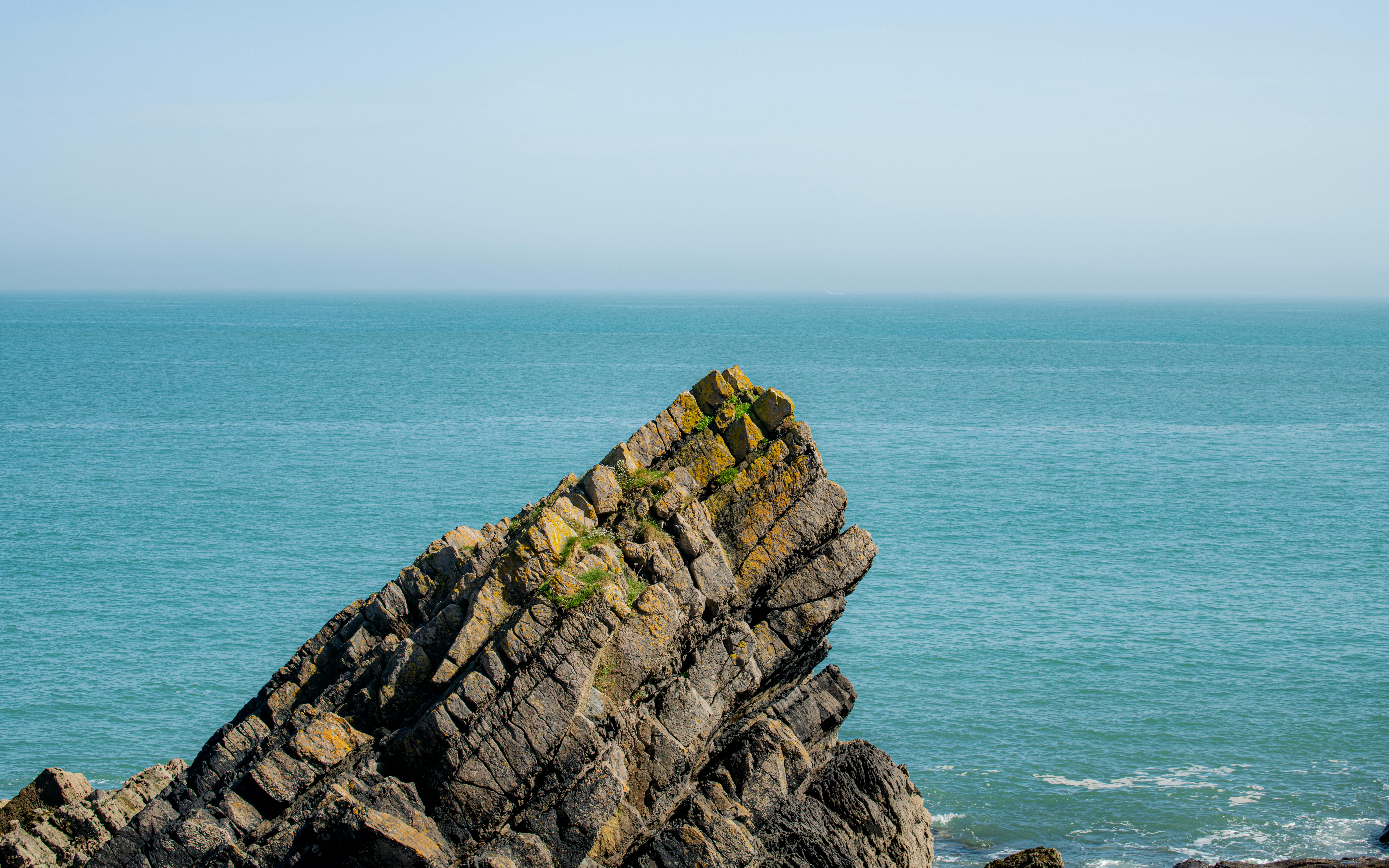 A striking rocky cliff formation against a tranquil blue sea horizon.
