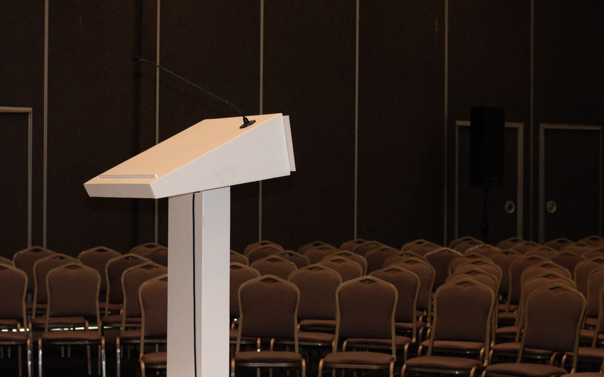 An empty conference room setup with podium and rows of chairs, ready for an event.