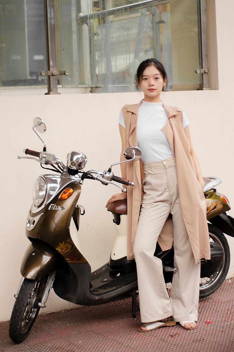 Confident Young Asian Woman Standing Near Scooter On Street