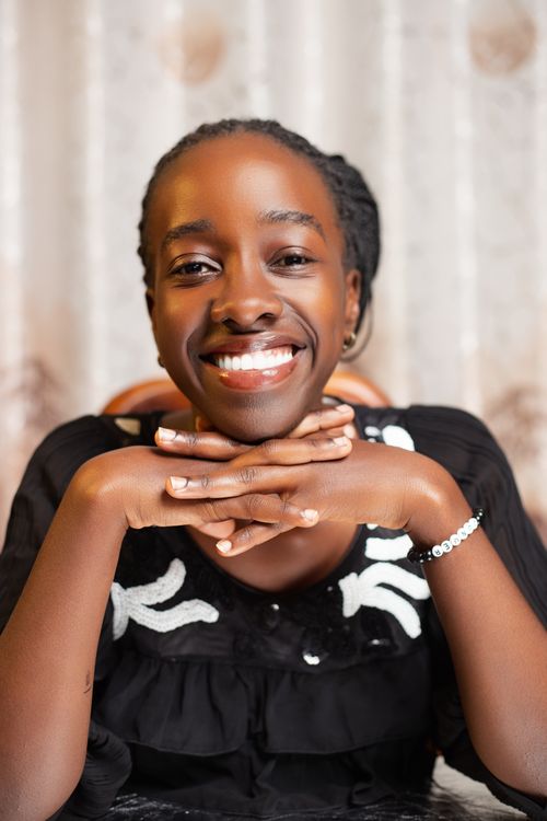 Free Portrait of a cheerful woman smiling indoors with her hands on her chin, creating a positive vibe. Stock Photo