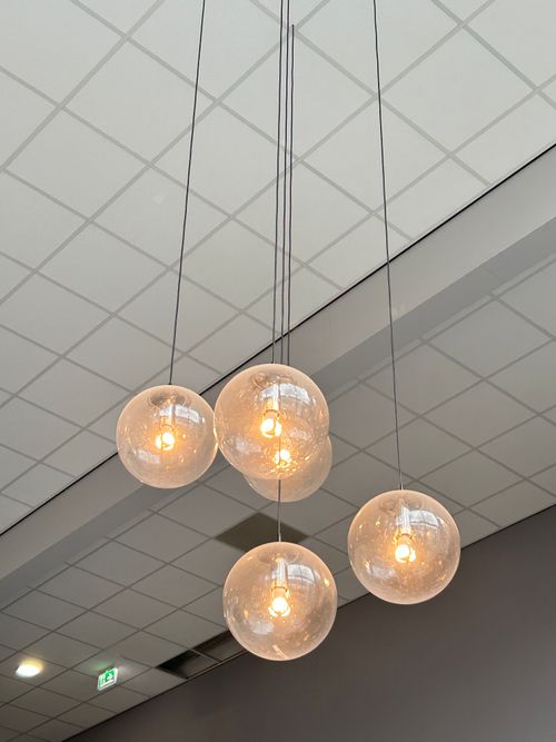 Free Contemporary interior with globe pendant lamps and grid ceiling design. Stock Photo