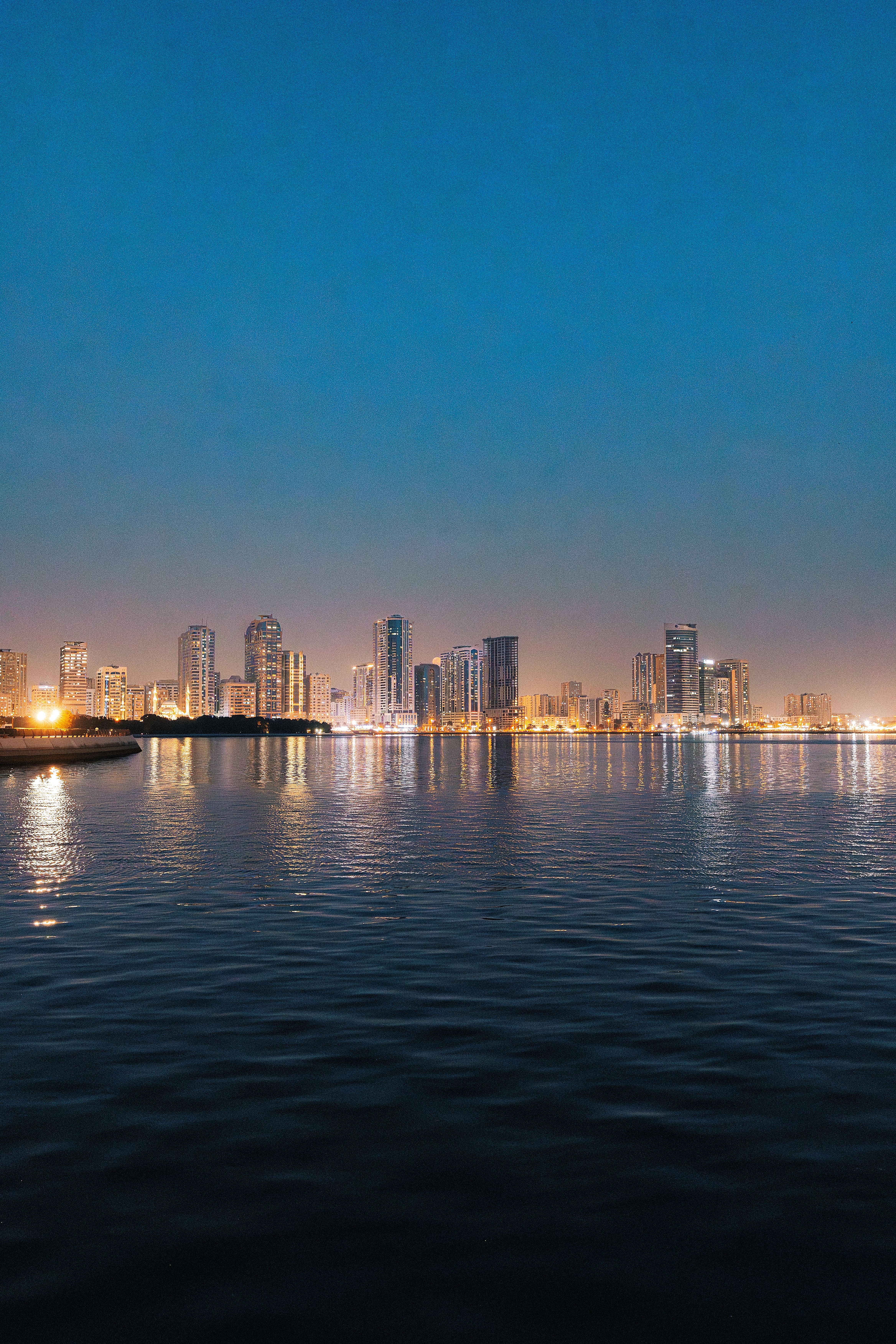 Stunning view of Dubai skyline reflecting on a river at twilight, showcasing illuminated skyscrapers.