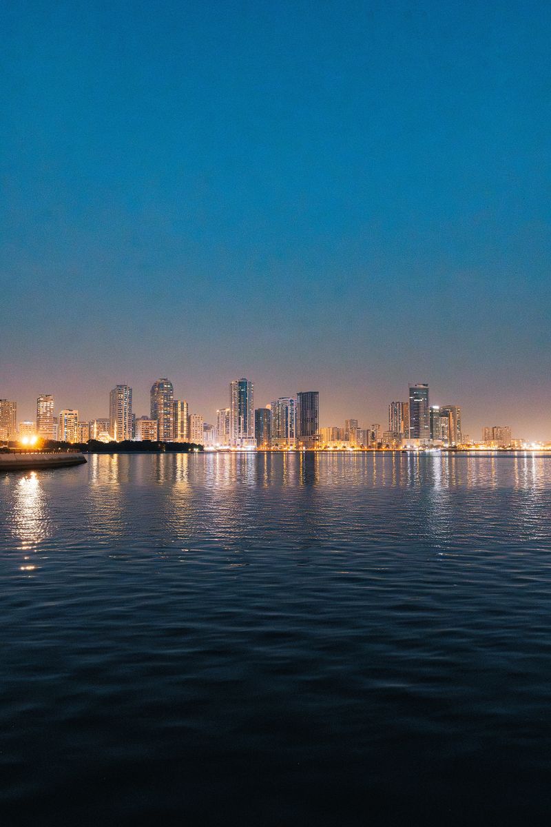 Stunning view of Dubai skyline reflecting on a river at twilight, showcasing illuminated skyscrapers.