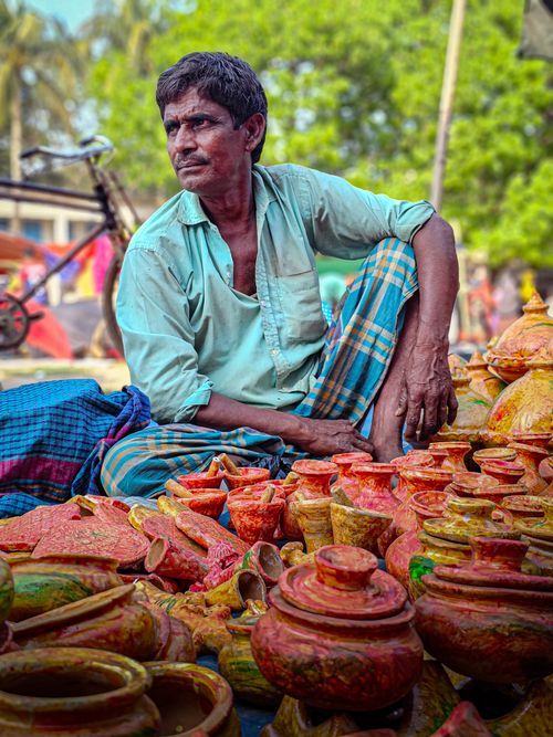 Free Man selling colorful clay pots at an outdoor market, showcasing traditional craftsmanship. Stock Photo
