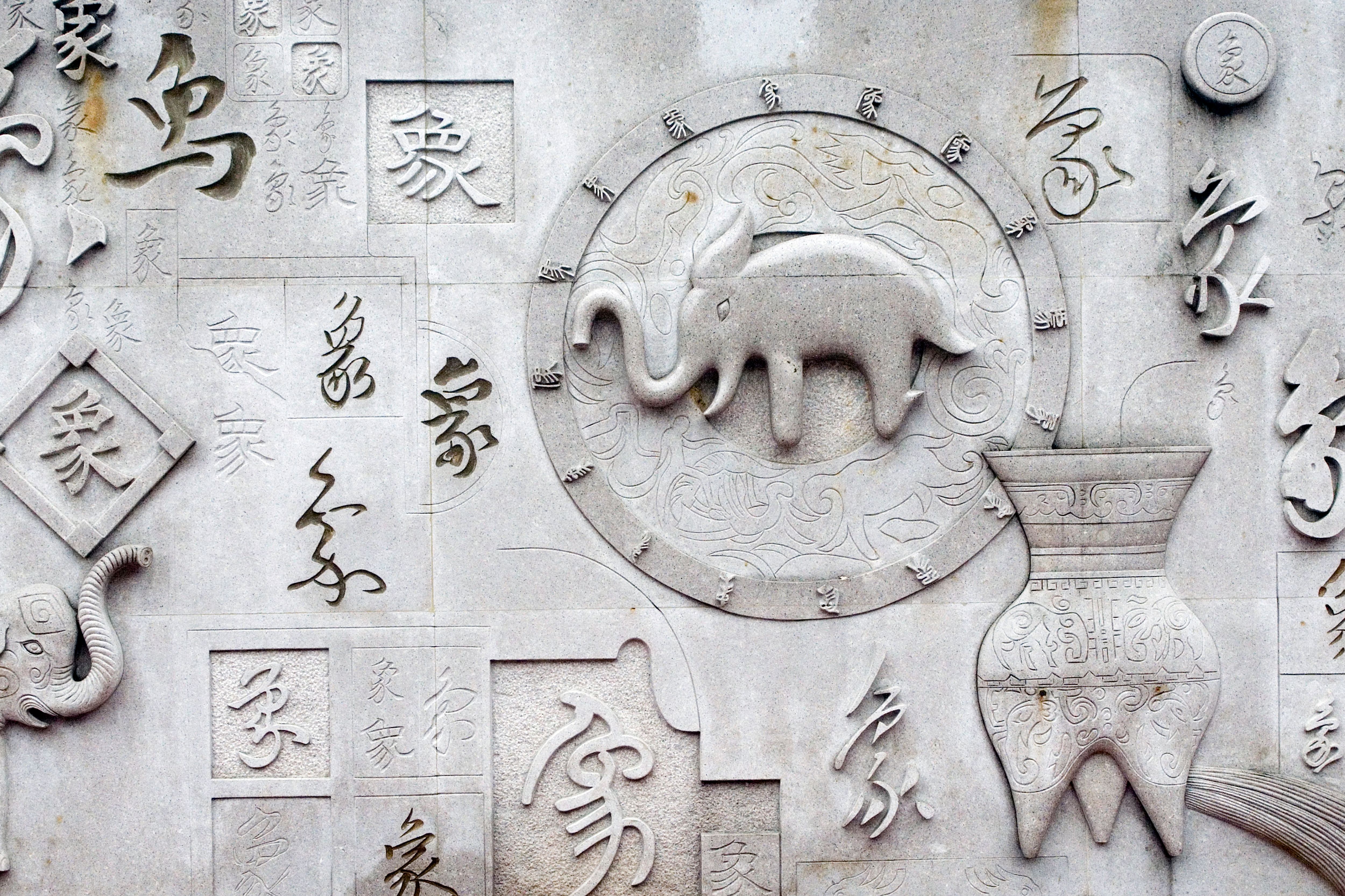 Detailed stone relief featuring Asian calligraphy, an elephant, and ornate patterns.