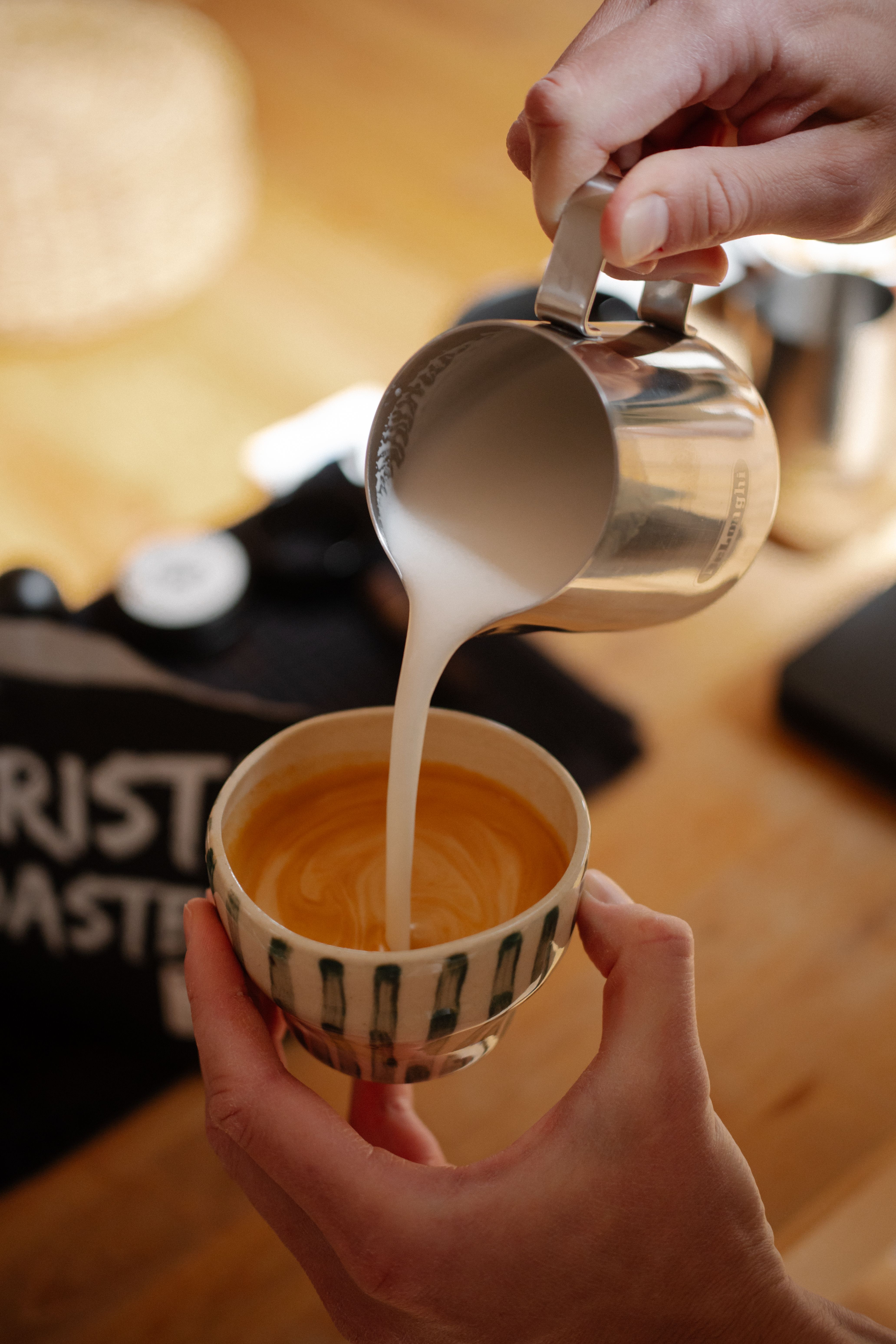 Close-up of steamed milk meeting espresso mid-pour, rosetta forming
