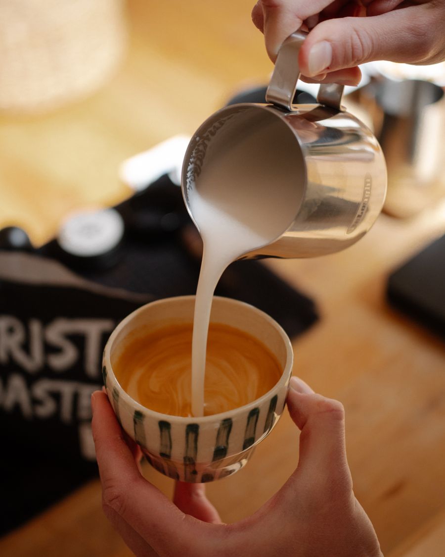 Steamed milk folding into espresso, captured mid-pour