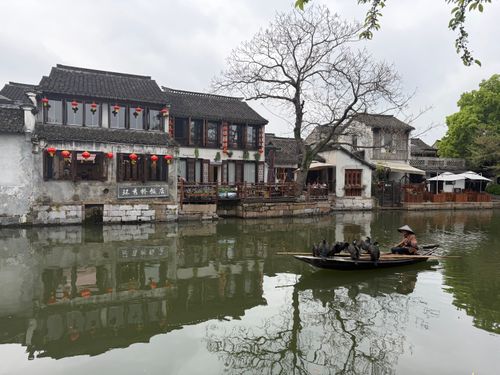 Free Fisherman in a boat at a tranquil water town, showcasing traditional buildings. Stock Photo