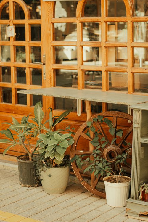 Free Charming outdoor café entrance with wagon wheel and potted plants. Stock Photo