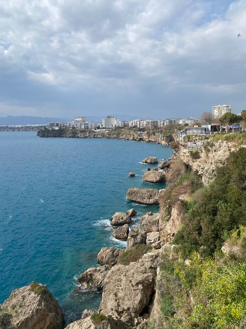 Free Stunning view of Antalya's rocky coastline with blue waters and cityscape. Stock Photo
