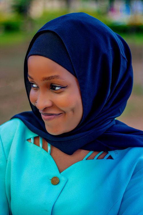 Free Portrait of a smiling woman wearing a blue hijab and turquoise shirt outdoors. Stock Photo