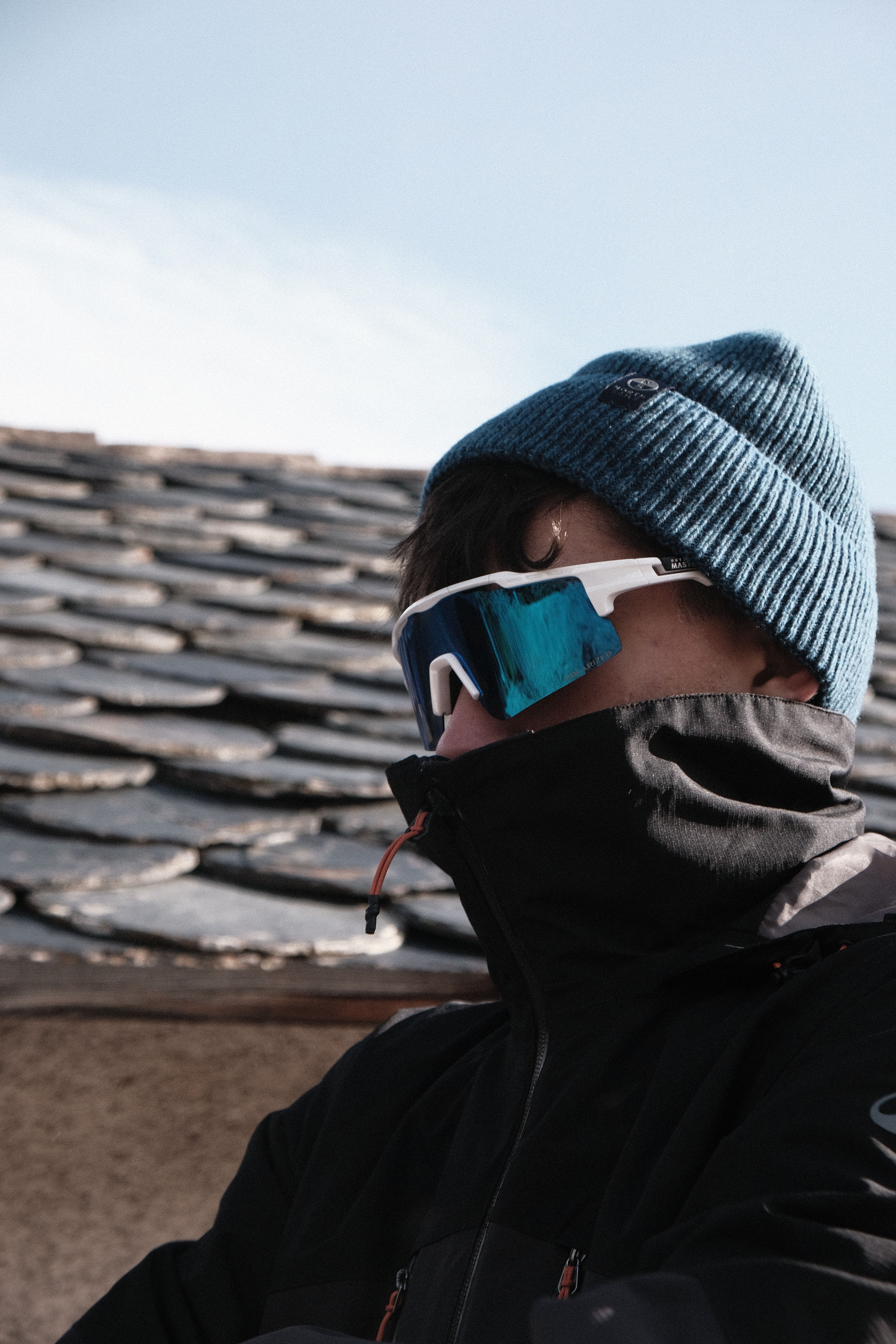 Person in a blue beanie and sunglasses in a cold setting, suggesting winter adventure.